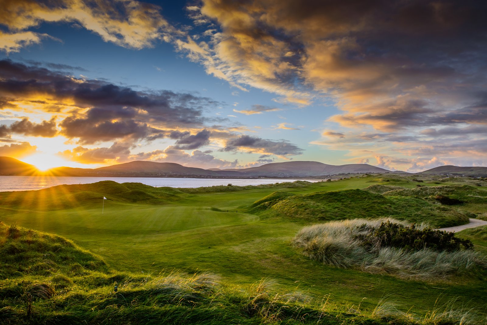 Links course at sunset, with dunes, a bay and low hills on the horizon, Ireland