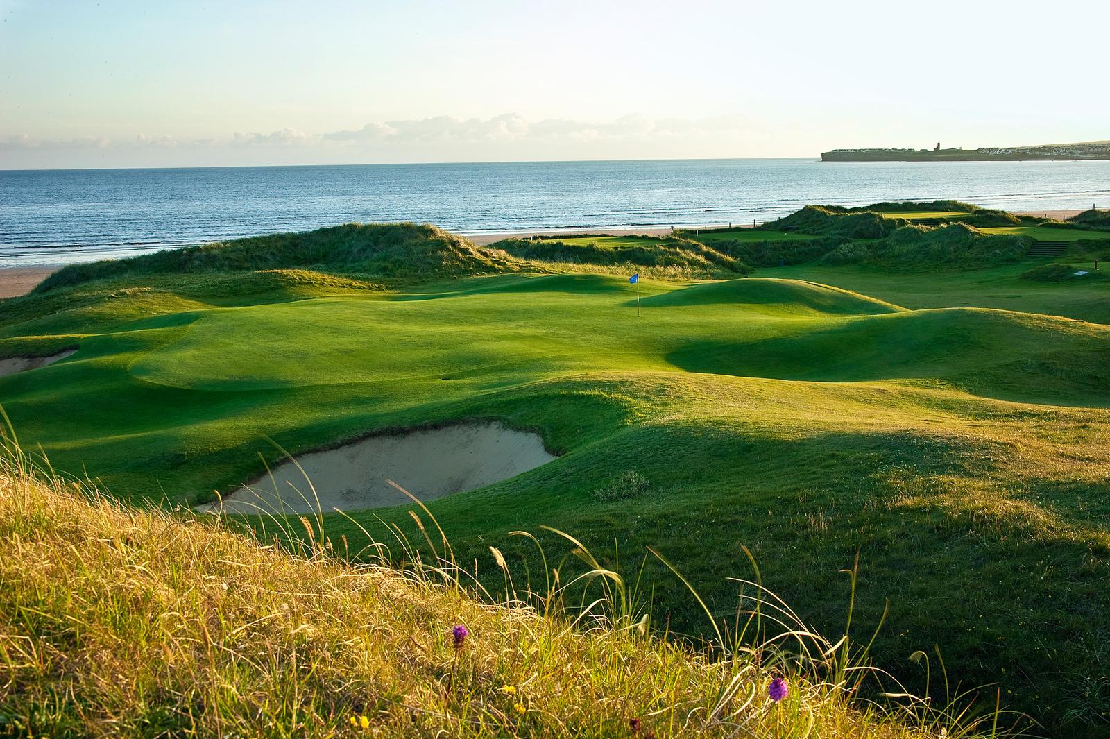 A links green and bunker set in grassy dunes above a long sandy beach on the west coast of Ireland